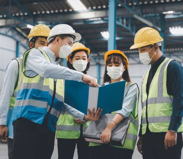 Site workers in hard hats and hi-vis reviewing a safety file